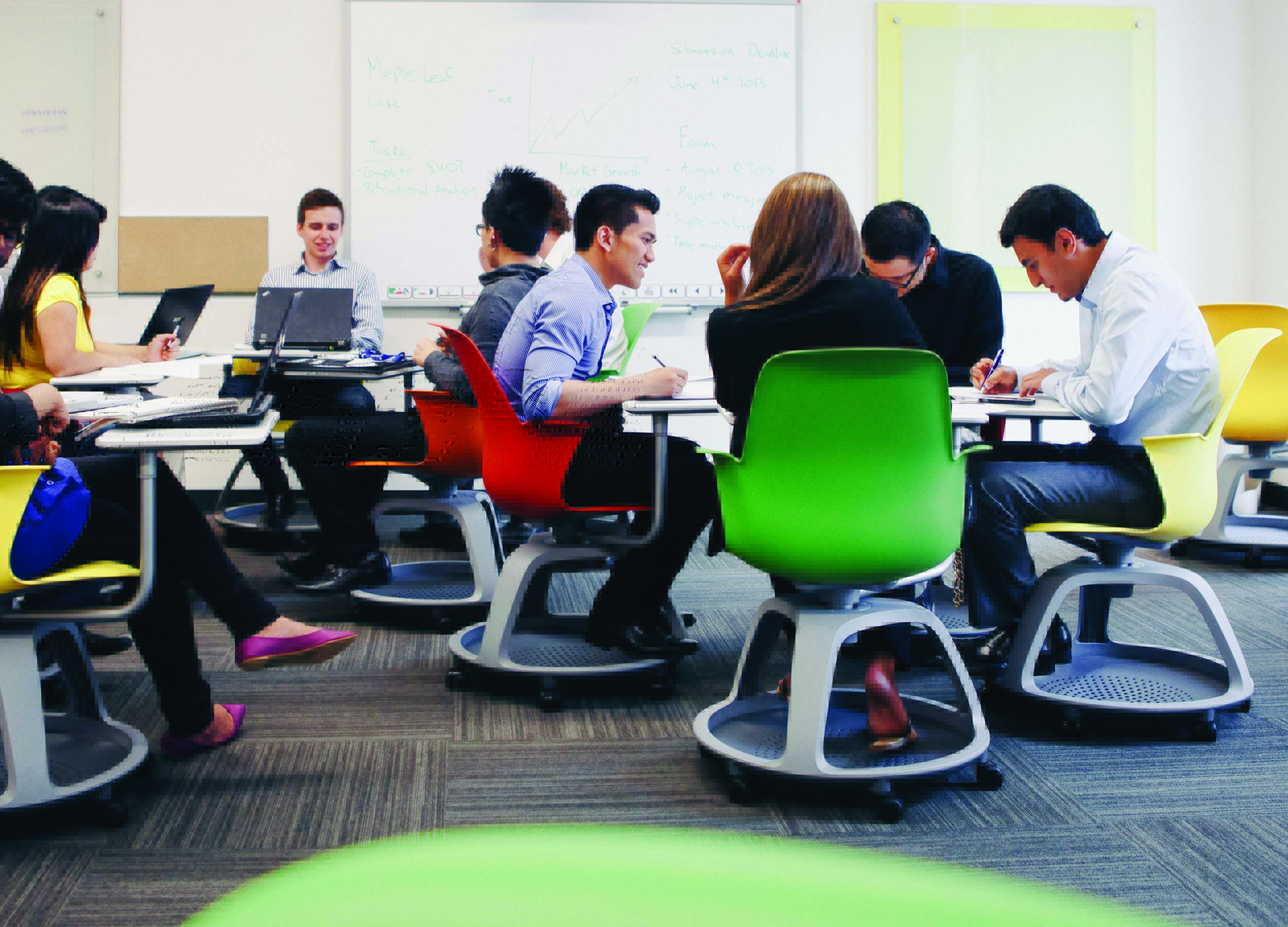 Students sitting in chairs around tables in a classroom